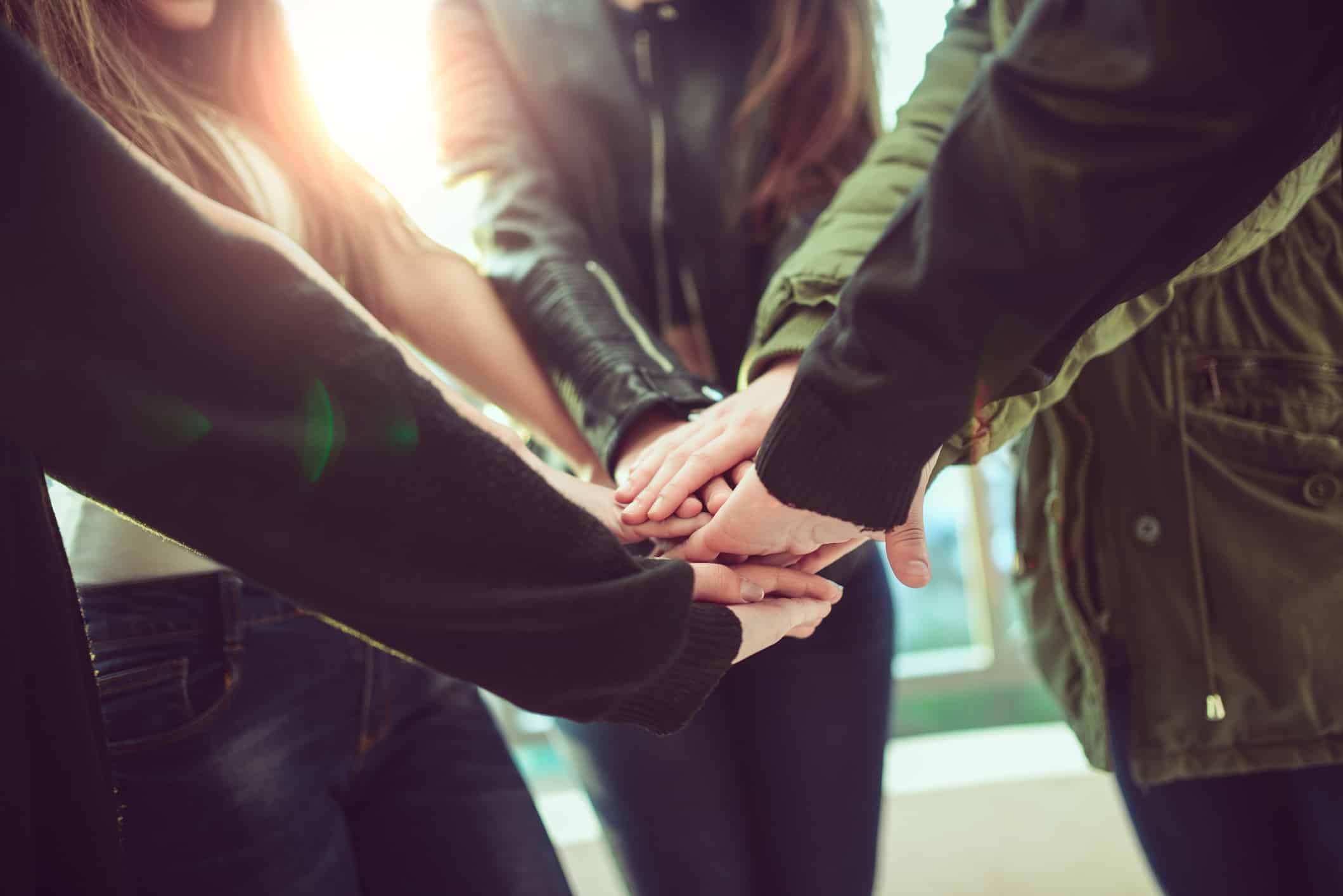 Group of Teenagers Volunteer Holding Hands in Circle for Teamwork