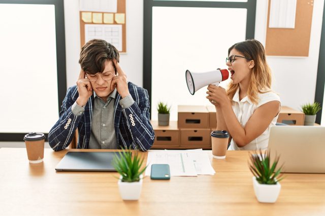 Businesswoman angry shouting her partner using megaphone at the office.